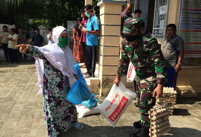 Ibu Aminah dengan dibantu Babinsa mengangkat bantuan yang diterimanya. FOTO h7 - nanda -
